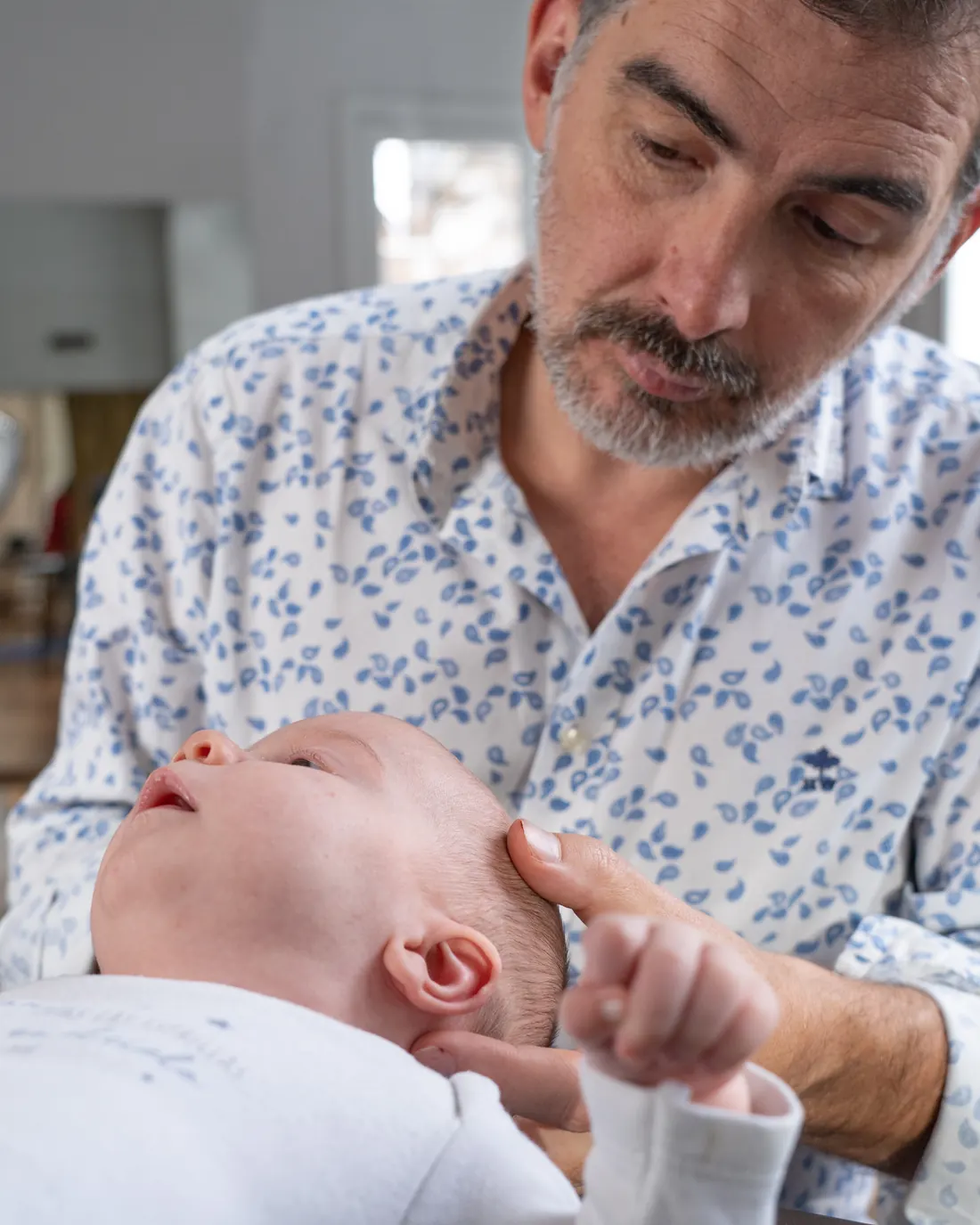 Fisioterapeuta avalia um bebê com as mãos, com atenção ao movimento da cabeça